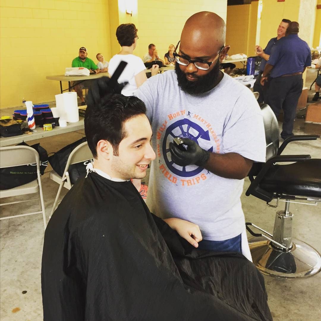 Leo cutting hair at community event